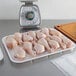 A white foam CKF meat tray filled with raw chicken legs on a counter in a butcher shop.