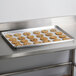 An Advance Tabco aluminum perforated sheet pan with cookies on a metal surface.