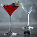 A Chef & Sommelier coupe glass filled with red liquid, blackberries, and rosemary on a table.