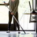A woman mopping the floor with a Lavex blue microfiber spray mop.