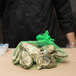 A person in a black jacket holding a green Royal Paper mesh bag with oysters.