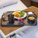 A black Dinex low profile room service tray with a plate of food, soup, and drinks on it.