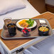 A gray Dinex Glasteel fiberglass tray holding a plate of food with a fork and spoon on a table.