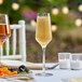 A table set with two Libbey plastic champagne flutes filled with champagne and a plate of fruit.