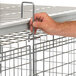 A hand holding a Cambro Camshelving Security Cage with a metal handle.