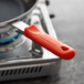 A red removable silicone pan handle sleeve on a pan handle.