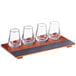 An Acopa wood tray with four whiskey tasting glasses on it.