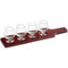 An Acopa mahogany finish flight paddle with four Belgian tasting glasses on it.