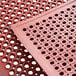 A red Choice anti-fatigue floor mat with holes in it.