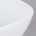 A close up of a CAC Citysquare bright white square porcelain bowl with curved edges.