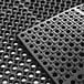 A Choice black rubber anti-fatigue floor mat with holes in it.