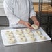 A chef using a Winholt plastic proofing board to prepare doughnuts.