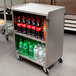 A Lakeside stainless steel utility cart with bottles of soda and water on it.