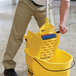 A man using a Rubbermaid WaveBrake mop bucket with a side press wringer to clean.