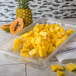 A Carlisle clear polycarbonate food pan drain tray with pineapple chunks on a counter.