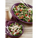 A salad with spinach, tomatoes, and cheese on a purple Fiesta® appetizer plate.