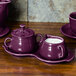 A purple Fiesta sugar and creamer tray set on a wooden surface.