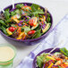 A Fiesta mulberry china bistro bowl filled with salad with colorful vegetables.