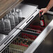 A hand opening a Beverage-Air bottle cooler drawer to get a beer.