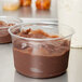 A Fabri-Kal clear plastic deli container filled with chocolate pudding.