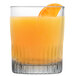 An Arcoroc tumbler filled with orange juice and a slice of orange.