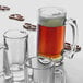 An Arcoroc glass mug filled with beer on a table.