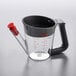 An OXO clear plastic measuring cup with a red handle and black lid.