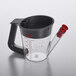 An OXO clear glass fat separator with a black handle.
