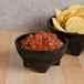 A Viva Mexico melamine molcajete bowl filled with salsa and chips on a table.