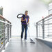 A woman using a ProTeam ProBlade vacuum tool to clean a floor.