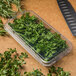 A clear plastic CKF clamshell container of parsley with a hook top and a knife.