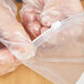 A person in plastic gloves holding a LK Packaging plastic food bag with a white write-on block.