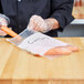 A person wearing a black coat using an LK Packaging plastic bag to put carrots in.