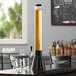 A Beer Tubes black conic beer tower on a table with glasses.