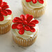 Three cupcakes with Satin Ice ChocoPan red flowers on top.