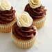 Three Satin Ice ChocoPan ivory cupcakes with chocolate frosting and white roses.