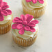 Three cupcakes with Satin Ice ChocoPan pink flowers on top.