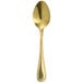 A close-up of a Walco gold stainless steel teaspoon with a white background.