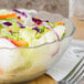 A Carlisle Petal Mist clear polycarbonate bowl filled with salad on a white background.