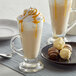 A table with two glass cups of UPOURIA White Chocolate Caramel Cappuccino and caramel sauce.