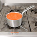 A Vollrath Wear-Ever sauce pan of red sauce on a stove.