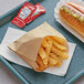 A tray with a Carnival King large Kraft French fry bag filled with fries and a hot dog with relish.