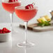 Two Arcoroc Coupe Cocktail glasses filled with raspberry cocktails and garnished with fresh raspberries.