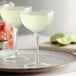 A pair of Arcoroc coupe cocktail glasses filled with green drinks on a plate.