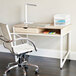 A white desk with a Safco Vamp LED desk lamp next to a white chair.