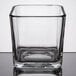 A square clear glass Libbey condiment jar on a reflective surface.