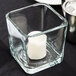 A Libbey cube glass candle holder with a white candle inside.