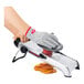 A gloved hand uses an OXO Chef's Mandoline Slicer to cut an orange.