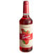 A Torani Puremade Strawberry Flavoring Syrup 750 mL glass bottle filled with red liquid with strawberries on it.