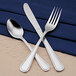 A stainless steel Libbey salad fork on a blue napkin.